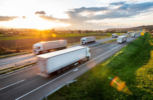 speeding trucks driving on highway at sunset