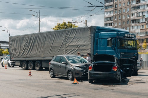 Blue semi-truck and several cars involved in a multi-vehicle accident on a city street